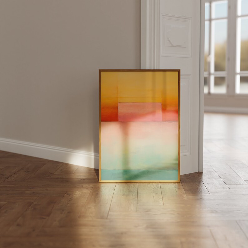 Peut inclure: Peinture abstraite dans un cadre dor&eacute; avec des nuances de jaune, de rose et de bleu. La peinture est appuy&eacute;e contre un mur blanc.