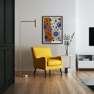 May include: A yellow armchair with black legs sits in a living room with a black floor lamp, a white wall, and a framed poster with the text "Yayoi Kusama" and a colorful abstract design.