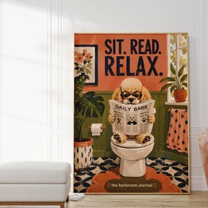 Könnte beinhalten: Ein rechteckiger Wandkunstdruck mit einem hellbraunen Pudel mit schwarzer Brille, der auf einer weißen Toilette sitzt und eine Zeitung namens Daily Bark liest. Der Hintergrund zeigt eine grüne Wand, eine Topfpflanze und ein rosa Handtuch mit schwarzen Punkten.