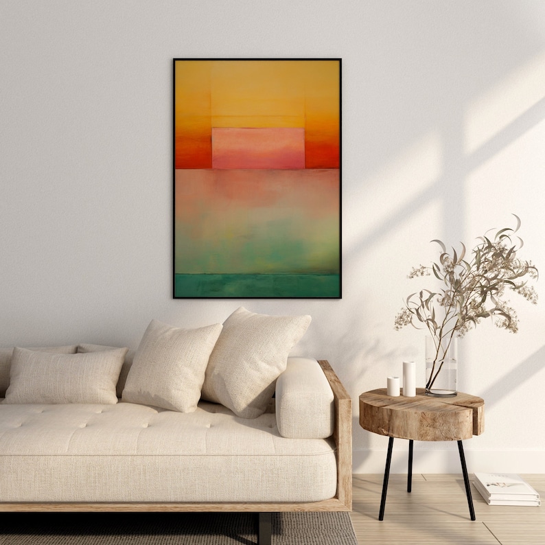Peut inclure: Peinture abstraite dans un cadre noir avec un sch&eacute;ma de couleurs jaune, orange, rose et vert. La peinture est accroch&eacute;e &agrave; un mur blanc au-dessus d'un canap&eacute; blanc avec des coussins.