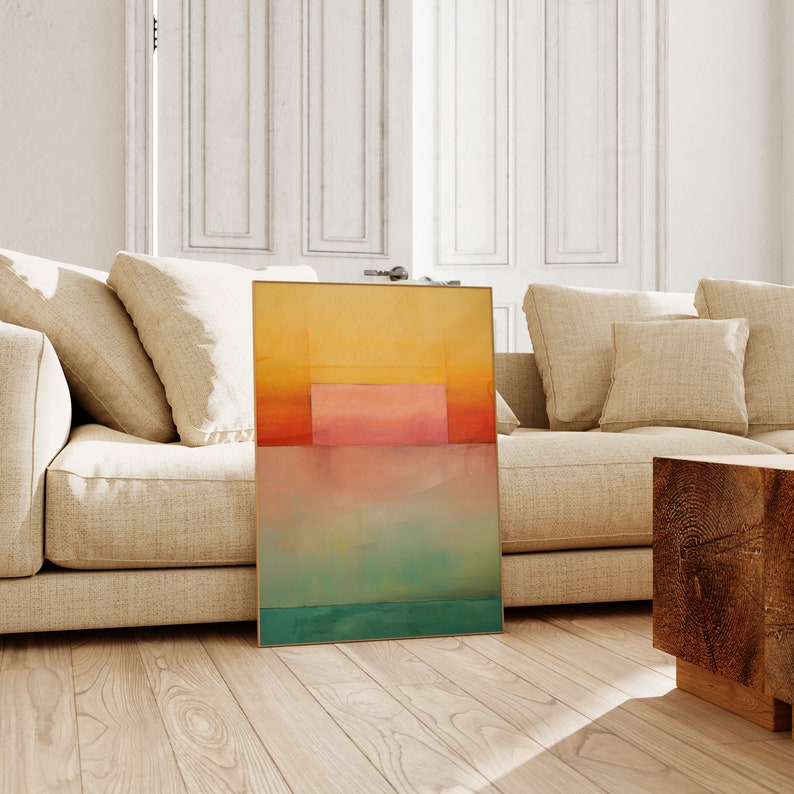 Peut inclure: Impression d'art abstrait avec un sch&eacute;ma de couleurs jaune, orange, rose, bleu et vert. L'impression est encadr&eacute;e dans un cadre dor&eacute; et est appuy&eacute;e contre un canap&eacute; beige.