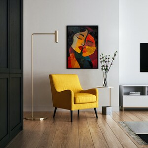 May include: A yellow armchair sits in a living room with a black and white abstract painting of two women's faces on the wall. A gold floor lamp stands next to the chair, and a small table with a vase of pink flowers sits in front of the chair.
