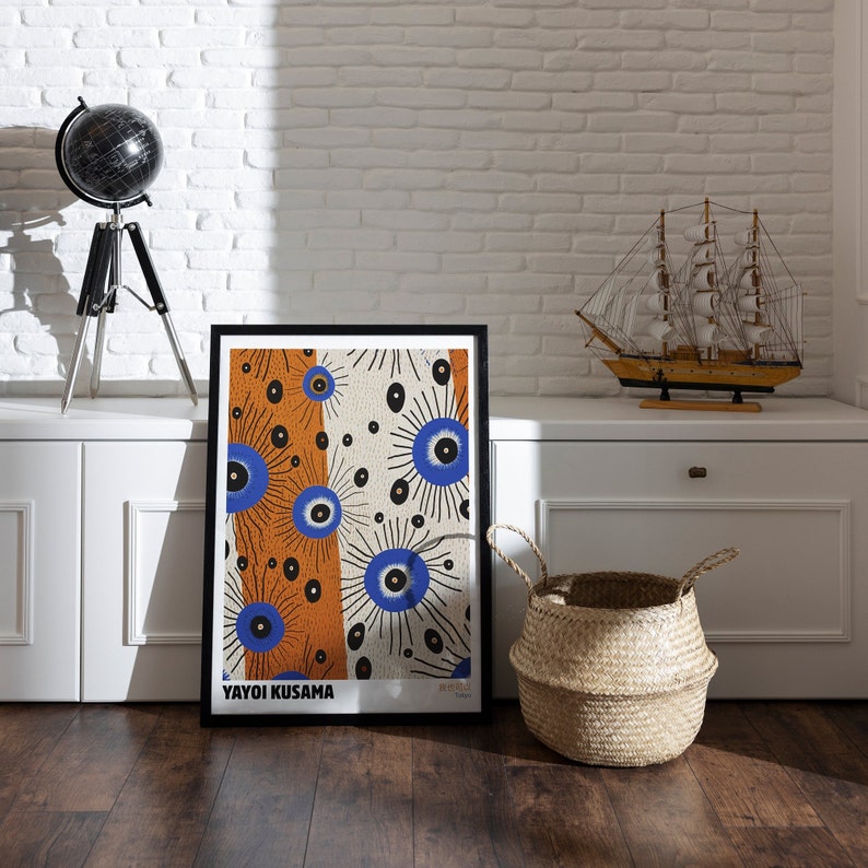 May include: A black framed print of a colorful abstract art piece with blue, orange, and white colors. The print features a repeating pattern of stylized eyes and is titled "Yayoi Kusama".