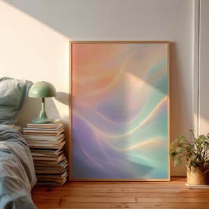 Könnte beinhalten: Ein rechteckiger gerahmter Wandkunstdruck mit einem weichen, ätherischen Farbverlauf in Pastellorange, Violett und Türkis mit fließenden, wellenartigen Lichtmustern. In der Mitte des Drucks befindet sich der kleine, blasse Text drift into calm.