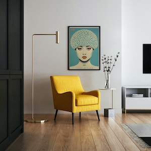 May include: A contemporary living room with a framed Yayoi Kusama art print. The artwork shows a woman with a polka-dot head covering. A yellow armchair with black legs is positioned below the print. A gold floor lamp and a side table with a vase of flowers are also visible.