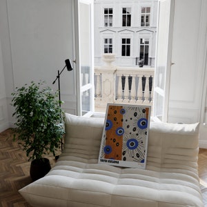May include: A white couch with a framed print of a colorful abstract design featuring blue and orange circles. The print is titled "Yayoi Kusama".