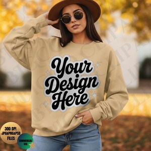 Może przedstawiać: Beżowa bluza z napisem "Your Design Here" czarną, stylizowaną czcionką. Bluza z długim rękawem ma okrągły dekolt. Obraz zawiera również brązowy kapelusz i okulary przeciwsłoneczne.
