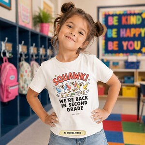 May include: A white short-sleeved t-shirt featuring a colorful graphic of three cartoon ducks. The text reads SQUAWK! WE'RE BACK IN SECOND GRADE EST. 2025. The design includes small illustrations of a pencil and paper airplane below the ducks.