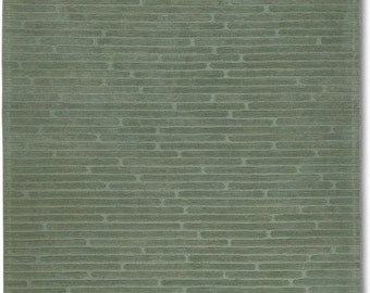 May include: A green rug with a textured pattern of horizontal lines and small ovals.