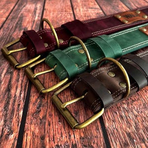 Premium leather dog collars in burgundy, green, and dark brown, handcrafted with antique brass buckles and sturdy D-rings.
