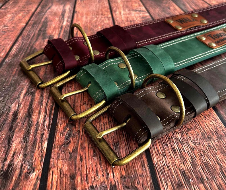 Premium leather dog collars in burgundy, green, and dark brown, handcrafted with antique brass buckles and sturdy D-rings.