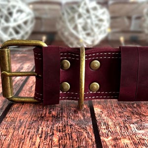 Wide burgundy leather dog collar with reinforced stitching, antique brass buckle, and heavy-duty D-ring for leash attachment.