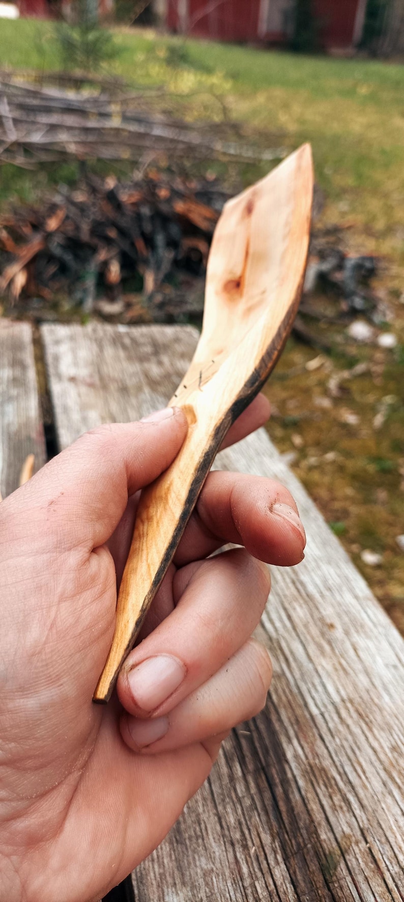 K&ouml;nnte beinhalten: Ein handgeschnitzter Holzl&ouml;ffel mit nat&uuml;rlicher, hellbrauner Oberfl&auml;che. Der L&ouml;ffel hat einen langen, schlanken Stiel und eine breite, flache Sch&uuml;ssel. Die Kanten des L&ouml;ffels sind dunkelbraun und zeigen die nat&uuml;rliche Rinde.