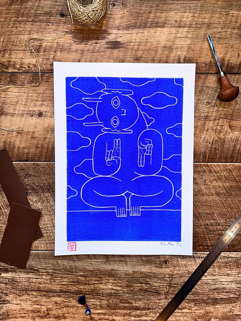 A captivating blue character emerges from a textured blue background in a linocut print. Intricate lines define its mystical pose, contrasting subtly against varying shades of blue, creating an enigmatic, mesmerizing effect.