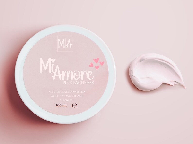 May include: A pink jar of face mask with the text "MiAmore Pink Facemask" and "Gentle clays combined with almond oil and vitamin E 100 mL e". A small pink swirl of the face mask is shown to the right of the jar.