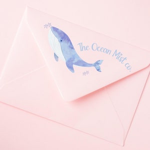 May include: A pink envelope with a blue watercolor whale illustration and the text "The Ocean Mist co."