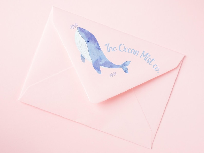 May include: A pink envelope with a blue watercolor whale illustration and the text "The Ocean Mist co."