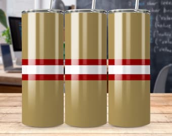 Pode incluir: Três copos de aço inoxidável dourados com listras vermelhas e brancas. Os copos estão sobre uma superfície de madeira.