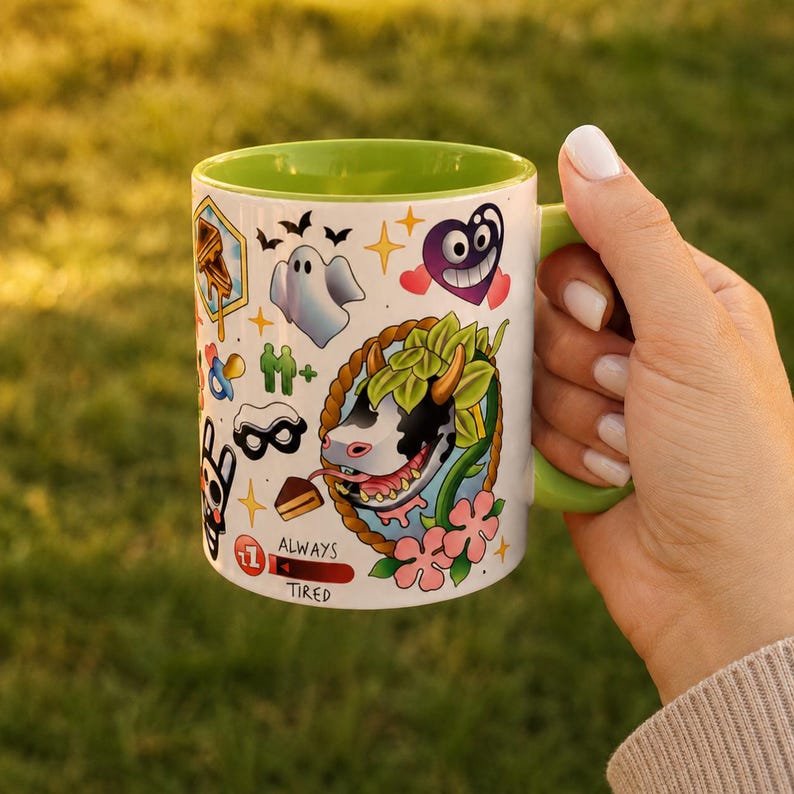 Pode incluir: Uma caneca de cer&acirc;mica branca com interior e al&ccedil;a verde-lim&atilde;o, apresentando uma estampa gr&aacute;fica colorida de uma cabe&ccedil;a de vaca, um fantasma, um cora&ccedil;&atilde;o roxo e v&aacute;rios &iacute;cones pequenos, incluindo uma fatia de bolo e o texto ALWAYS TIRED.