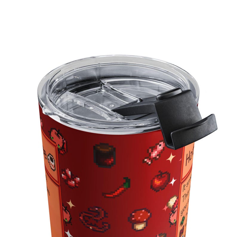 Puede incluir: Un vaso de viaje rojo con tapa transparente y asa negra. El vaso presenta gr&aacute;ficos de alimentos pixelados, incluyendo un chile, una manzana y una seta. El texto en el lateral dice "Hot Stuff".