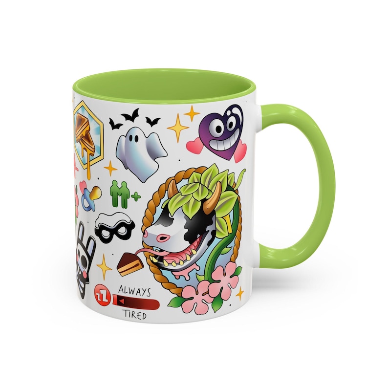 Pode incluir: Uma caneca de cer&acirc;mica branca com interior e al&ccedil;a verde-lim&atilde;o, apresentando uma colagem colorida em estilo tatuagem de uma vaca, um fantasma, um cora&ccedil;&atilde;o roxo, um waffle e outros &iacute;cones, incluindo uma barra de progresso vermelha com o texto ALWAYS TIRED.