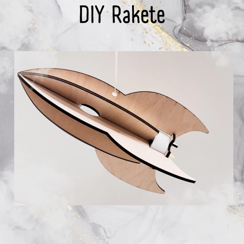 Może przedstawiać: Drewniany zestaw do samodzielnego wykonania rakiety z napisem "DIY Rakete" na g&oacute;rze. Rakieta wykonana jest z jasnobrązowego drewna i ma białą papierową rurkę z tyłu.