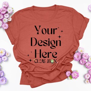 Pode incluir: Uma camiseta cor de ferrugem com o texto "Your Design Here" e "Club Mox" impresso na frente.