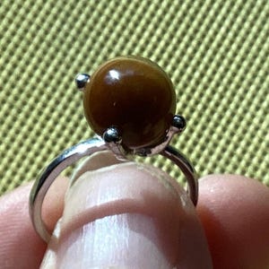May include: A silver ring with a brown tiger's eye gemstone.