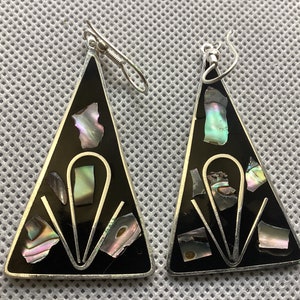 Puede incluir: Un par de pendientes triangulares de plata con esmalte negro e incrustaciones de abulón iridiscente.