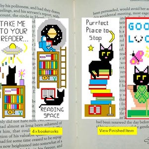 May include: Four pixel art bookmarks with cat and space themes. One says "Take Me To Your Reader..." with a UFO. Another says "Reading Space". The third says "Purrfect Place to Stop". The last says "Good Luck".