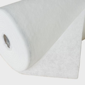 May include: A roll of white non-woven fabric material with a fibrous, textured surface. The roll is tightly wound around a central cardboard core, with a portion of the fabric extending outward to reveal the consistent, semi-translucent white finish.