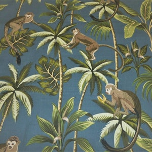May include: A blue fabric with a repeating pattern of monkeys and palm trees. The monkeys are brown and have long tails. The palm trees are green and have white fronds.