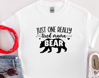 May include: White t-shirt with black text that reads "Just one really tired mama bear" and a black silhouette of a bear.
