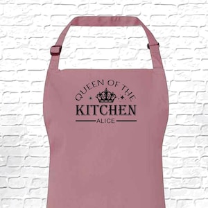 May include: A pink kitchen apron with the text "Queen of the Kitchen - Alice" and a crown graphic.