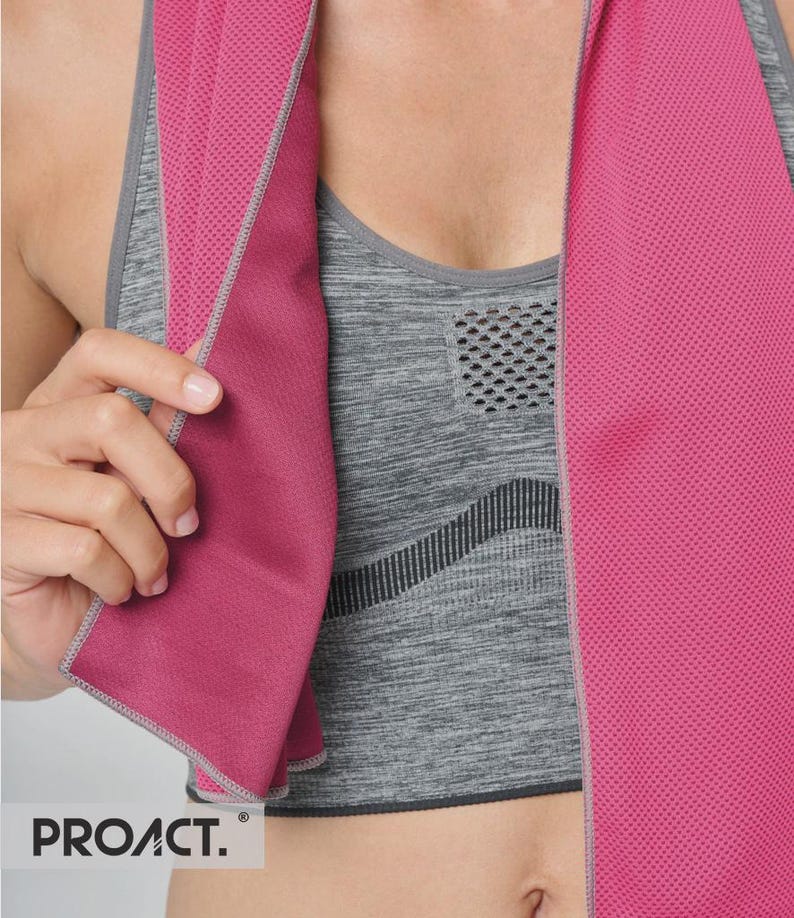Op de afbeelding: Een roze sportdoek met een mesh textuur is over een grijze sportbeha gedrapeerd. De handdoek heeft een grijze rand en de merknaam "PROACT." is linksonder zichtbaar. De sportbeha heeft een gestructureerd patroon.