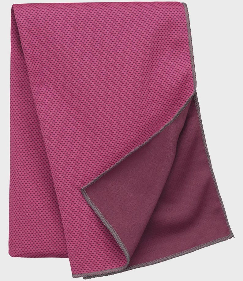 Op de afbeelding: Een opgevouwen magenta koelhanddoek met een getextureerd, gestippeld oppervlak. De onderkant van de handdoek is effen donkerder magenta, met een grijze gestikte rand. De handdoek is ontworpen om te koelen en wordt waarschijnlijk gebruikt voor sport of buitenactiviteiten.