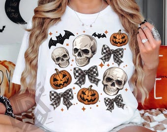Może przedstawiać: Biała koszulka z motywem Halloween. Projekt zawiera czaszki, dynie i szachownicowe kokardy. Nietoperze i gwiazdy są również uwzględnione. Tekst "SUBLIMATION DESIGN DIGITAL PNG" znajduje się na dole.