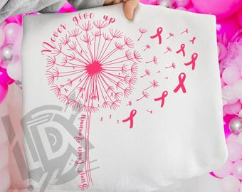 May include: White sweatshirt featuring a pink dandelion design with the words "Never Give Up" and "Breast Cancer Awareness." Pink ribbons are scattered across the design. The bottom of the image has the text "300 DPI SUBLIMATION DESIGN PNG."