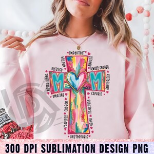 May include: A pink sublimation design featuring a colorful cross with the word "MOM" in the center. The cross is surrounded by words describing a mother, such as "blessed", "worthy", "strong", "capable", "fearless", "chosen", "unstoppable", "important", "never alone", "always enough", "victorious", "beautiful", and "loved".