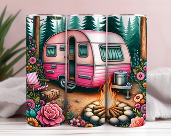 Op de afbeelding: Een roze en witte vintage camper met een kampvuur ervoor. De camper is omringd door groene bomen en kleurrijke bloemen. De scène is afgebeeld op een set van drie roestvrijstalen tumblers.