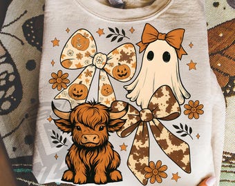 May include: A beige sweatshirt featuring a Halloween-themed design. The design includes a ghost, a Highland cow, and decorative bows with pumpkin and cow print patterns. The text "300 DPI SUBLIMATION DESIGN PNG" is at the bottom.