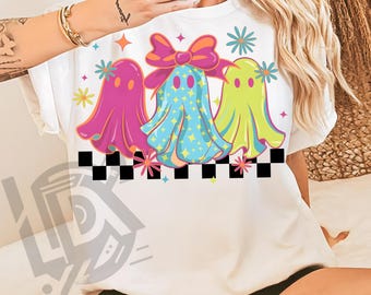 May include: White t-shirt featuring a colorful graphic of three cartoon ghosts. The ghosts are in pink, blue, and green, with star and flower accents. A black and white checkered pattern is at the bottom. Text at the bottom reads "300 DPI SUBLIMATION DESIGN PNG".