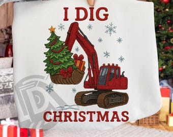 Puede incluir: Sudadera blanca con un diseño navideño. El diseño presenta una excavadora roja con un árbol de Navidad en su cuchara, copos de nieve y el texto "I DIG CHRISTMAS" en rojo. Una estrella adorna el árbol.