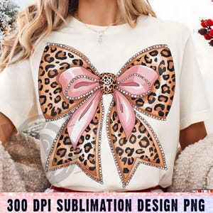 May include: A sublimation design featuring a large pink bow with a leopard print pattern and rhinestones. The bow is on a white background.