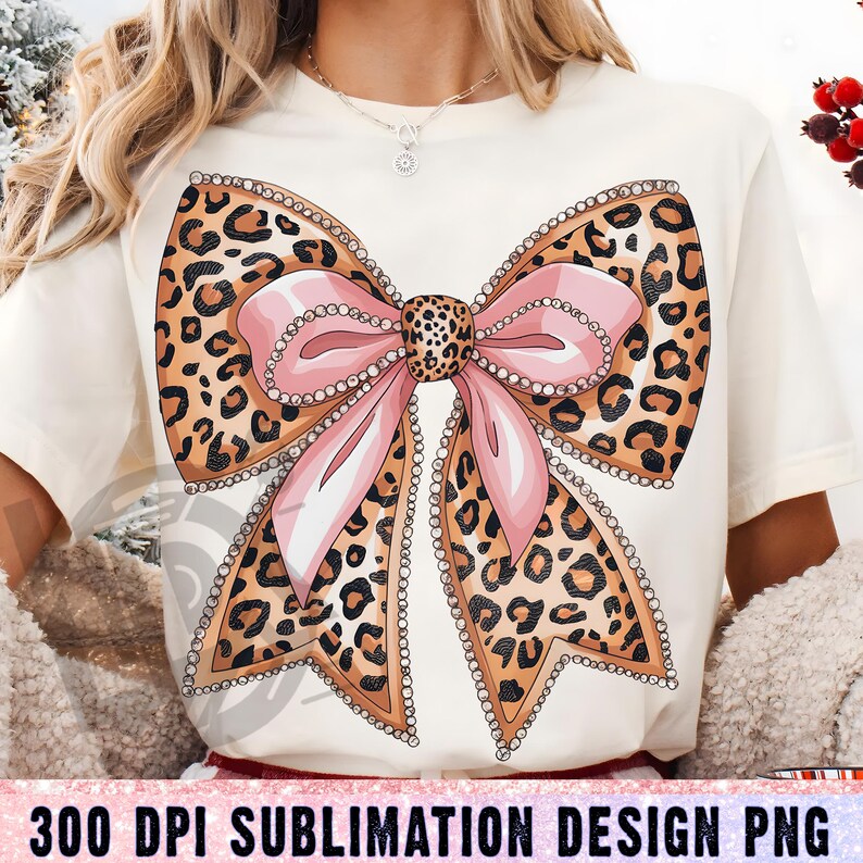 May include: A sublimation design featuring a large pink bow with a leopard print pattern and rhinestones. The bow is on a white background.