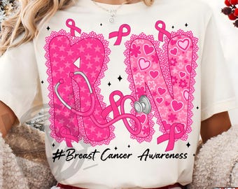 May include: White t-shirt featuring the letters "RN" in pink, decorated with stars, hearts, and lace. A pink stethoscope is draped across the letters. The text "#Breast Cancer Awareness" is below the letters. Pink ribbons are also present.