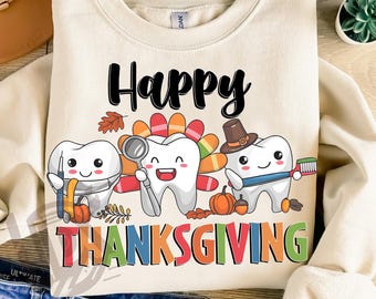 May include: Cream-colored sweatshirt with a Thanksgiving-themed graphic. The design features three cartoon teeth dressed as turkeys, holding dental tools and a toothbrush, with the words "Happy Thanksgiving" in black and colorful letters. Pumpkins and fall leaves are also included.
