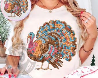 Pode incluir: Camiseta creme com um design de peru colorido em estilo mosaico. O peru tem uma cauda vibrante com quadrados azuis, laranja e marrons. O texto "300 DPI SUBLIMATION DESIGN PNG" é impresso na parte inferior.