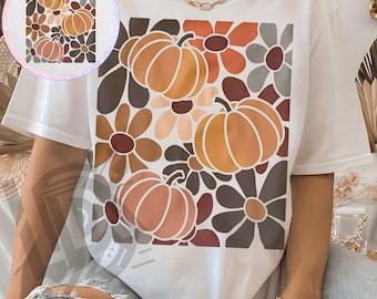 Op de afbeelding: Wit T-shirt met een herfstthema. Het ontwerp bevat oranje pompoenen en bloemmotieven in bruin, oranje en crème tinten. De tekst "300 DPI SUBLIMATION DESIGN PNG" staat onderaan het shirt.