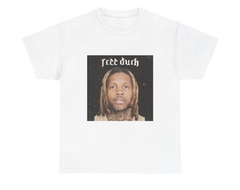 Op de afbeelding: Wit T-shirt met een zwart-witte afbeelding van een man met dreadlocks. De afbeelding bevat de tekst "free duck" boven het hoofd van de man.